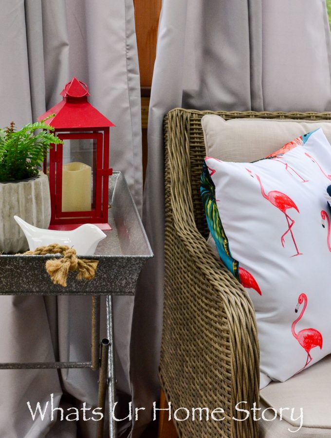 Love this outdoor space with a beautiful red and blue outdoor decor with a flamingo pillow, metal tray side table, and loads of green plants